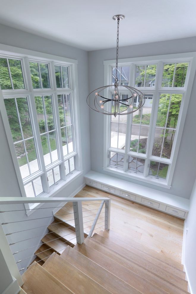 Mid-sized transitional wooden u-shaped cable railing staircase photo in Grand Rapids with wooden risers