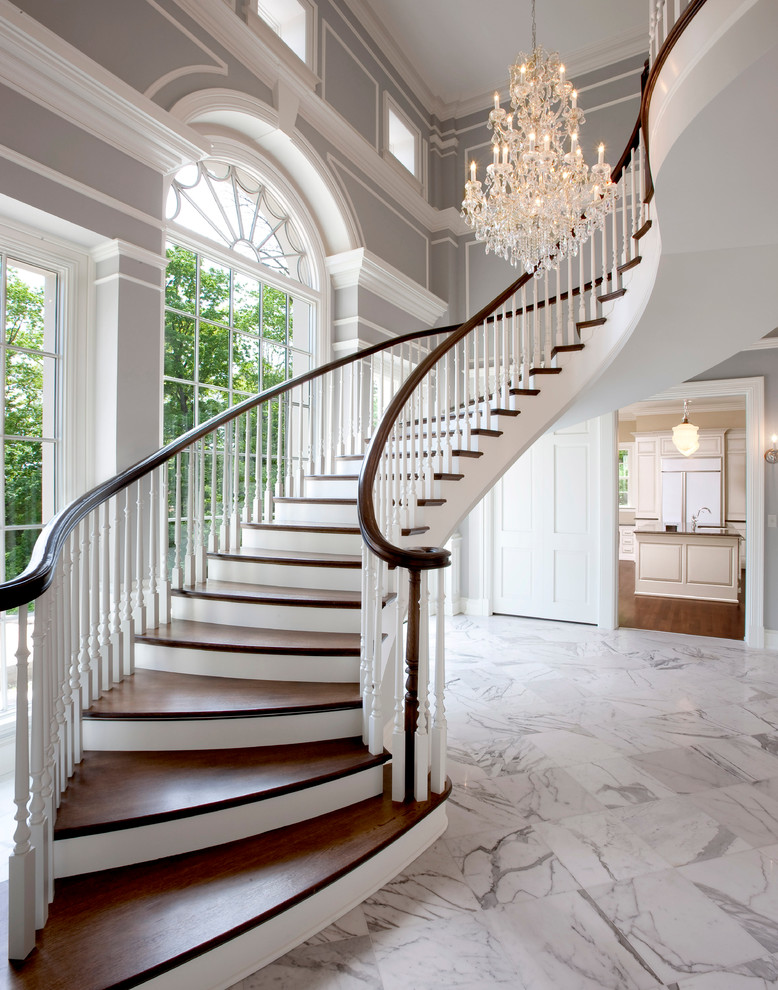 Aménagement d'un escalier peint courbe classique avec des marches en bois et un garde-corps en bois.