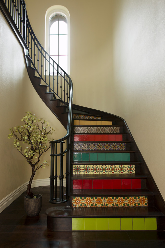 Ejemplo de escalera curva mediterránea con escalones de madera y contrahuellas con baldosas y/o azulejos
