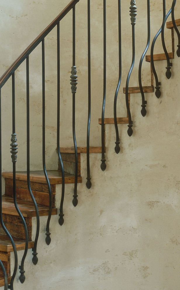 Imagen de escalera de caracol rústica grande con escalones de madera, contrahuellas de madera y barandilla de metal