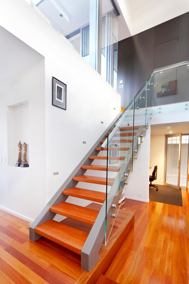 Imagen de escalera recta contemporánea de tamaño medio sin contrahuella con escalones de madera y barandilla de vidrio