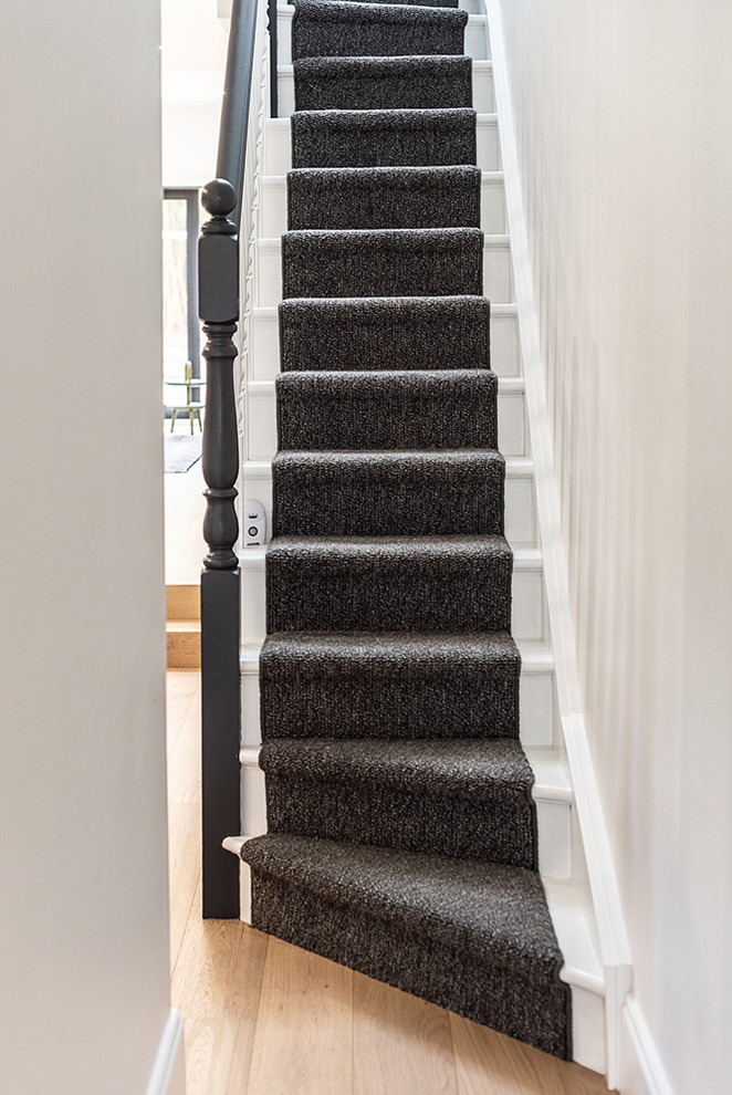 Imagen de escalera recta contemporánea pequeña con escalones de madera, contrahuellas enmoquetadas y barandilla de madera