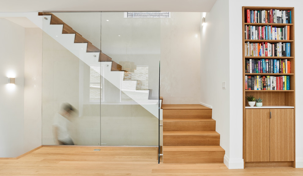 This is an example of a medium sized wood l-shaped glass railing staircase in Toronto with wood risers.