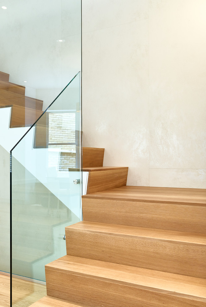 Пример оригинального дизайна: угловая лестница среднего размера с деревянными ступенями, стеклянными подступенками и стеклянными перилами