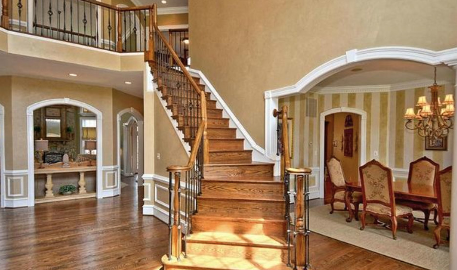 Стильный дизайн: большая изогнутая деревянная лестница в классическом стиле с деревянными ступенями - последний тренд