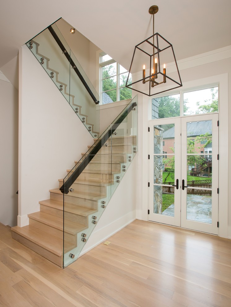 Cette image montre un escalier design avec des marches en bois, des contremarches en bois et un garde-corps en verre.