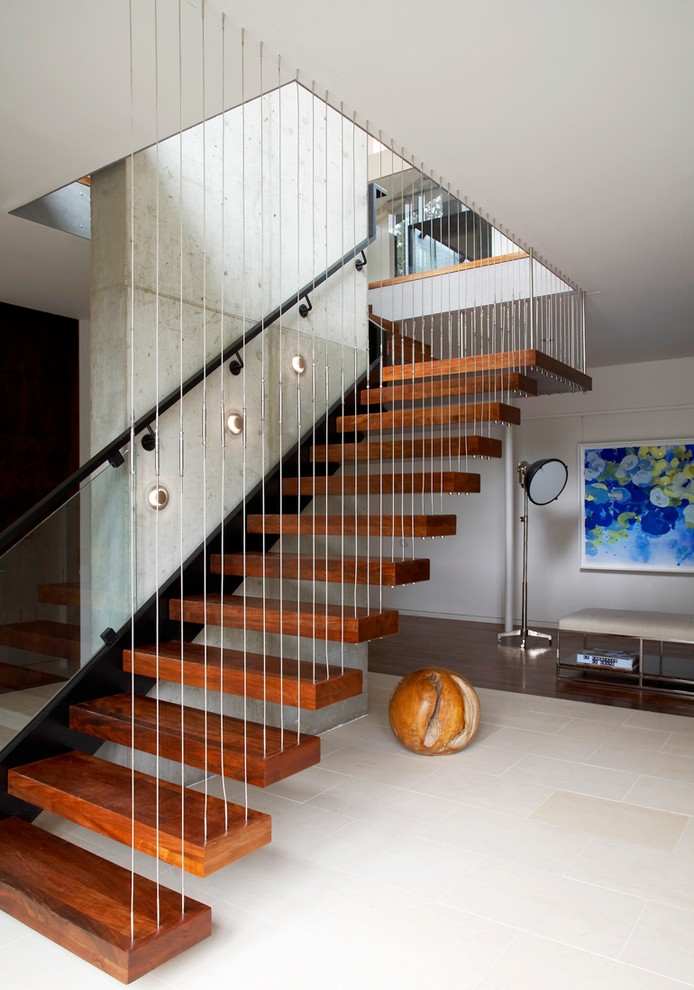 Cette image montre un escalier flottant minimaliste avec des marches en bois et éclairage.