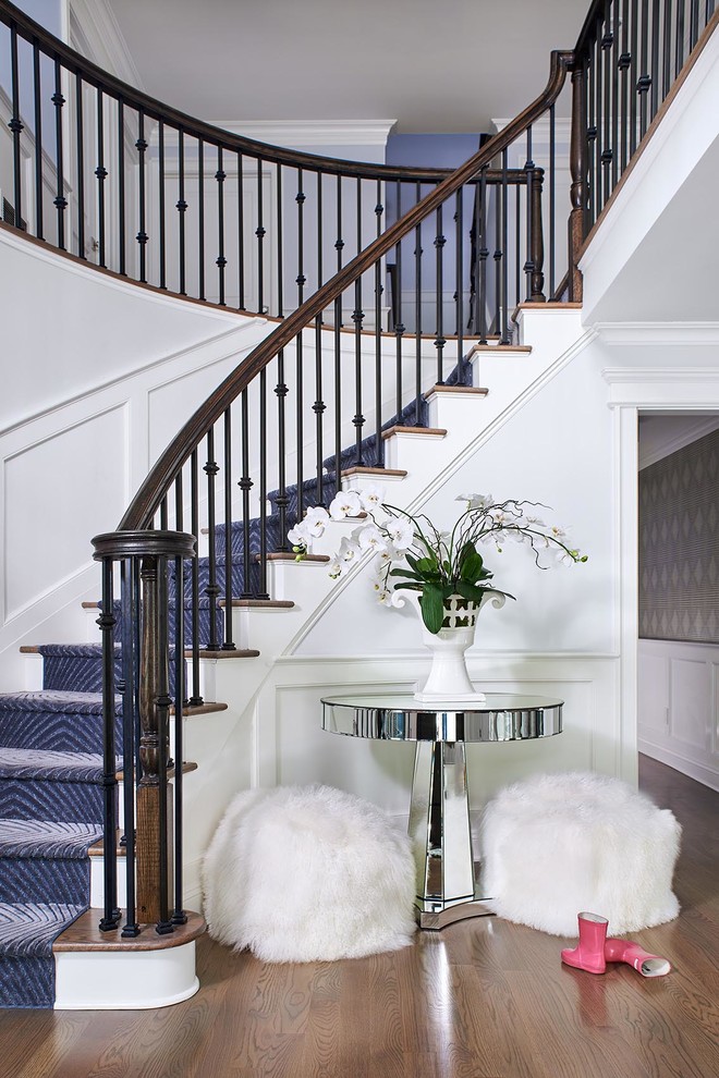Идея дизайна: изогнутая лестница в стиле неоклассика (современная классика) с деревянными ступенями, крашенными деревянными подступенками и металлическими перилами