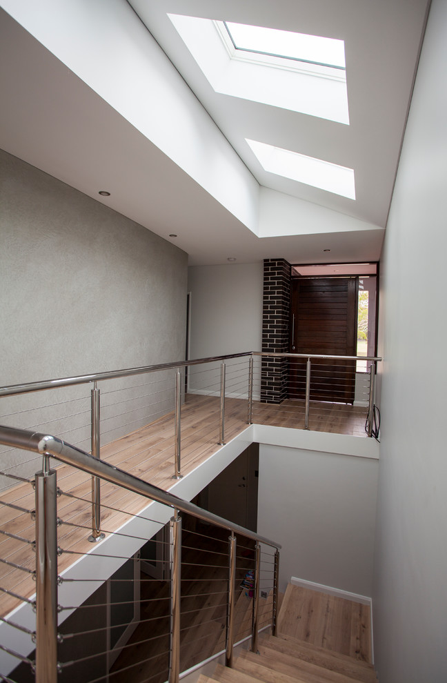 Ejemplo de escalera en L contemporánea con escalones de madera, contrahuellas de madera y barandilla de metal