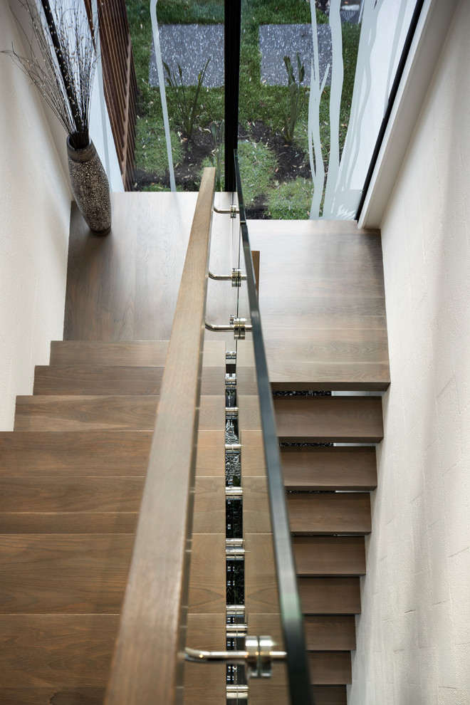 Foto di una scala a "U" contemporanea di medie dimensioni con pedata in legno, nessuna alzata e parapetto in vetro