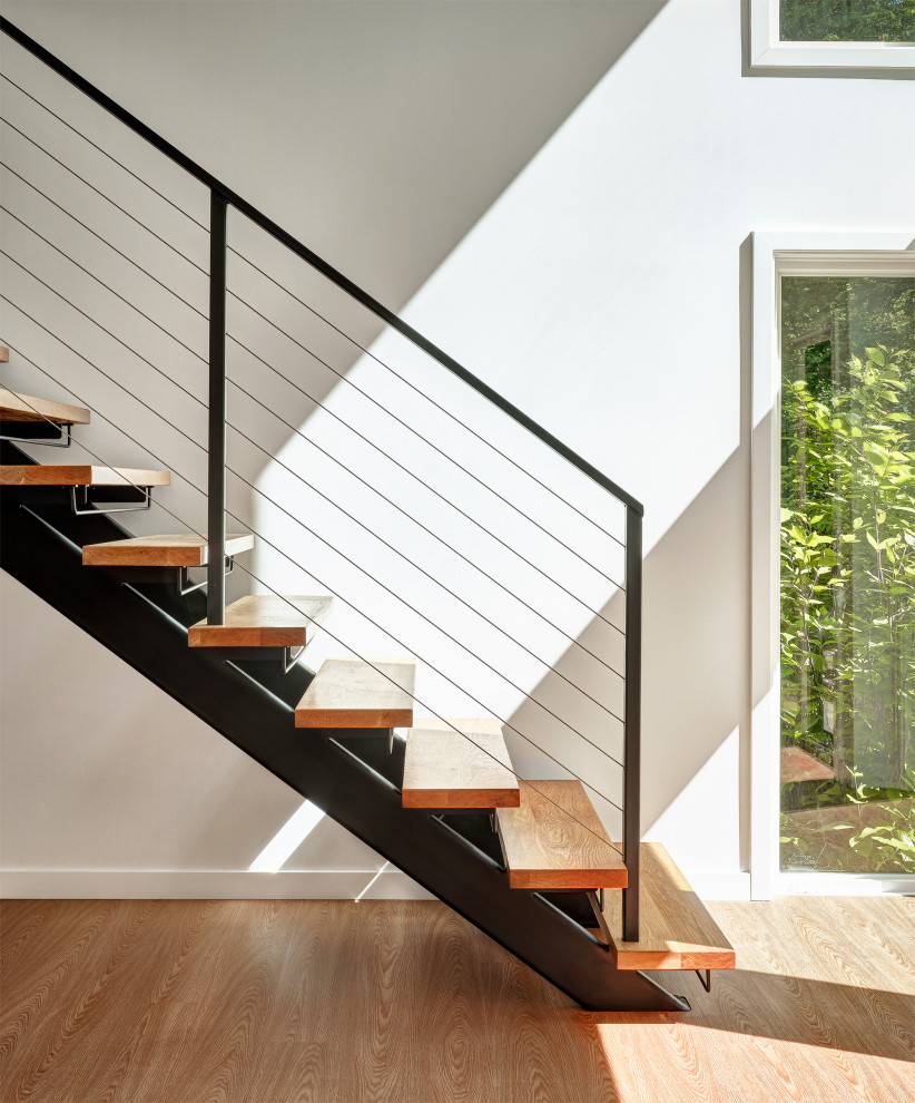 Foto de escalera recta minimalista de tamaño medio sin contrahuella con escalones de madera y barandilla de metal