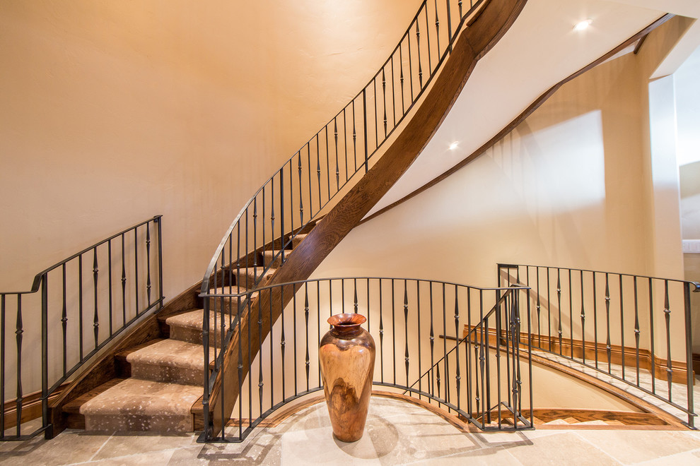 Diseño de escalera curva tradicional de tamaño medio con escalones de madera, contrahuellas de madera y barandilla de metal