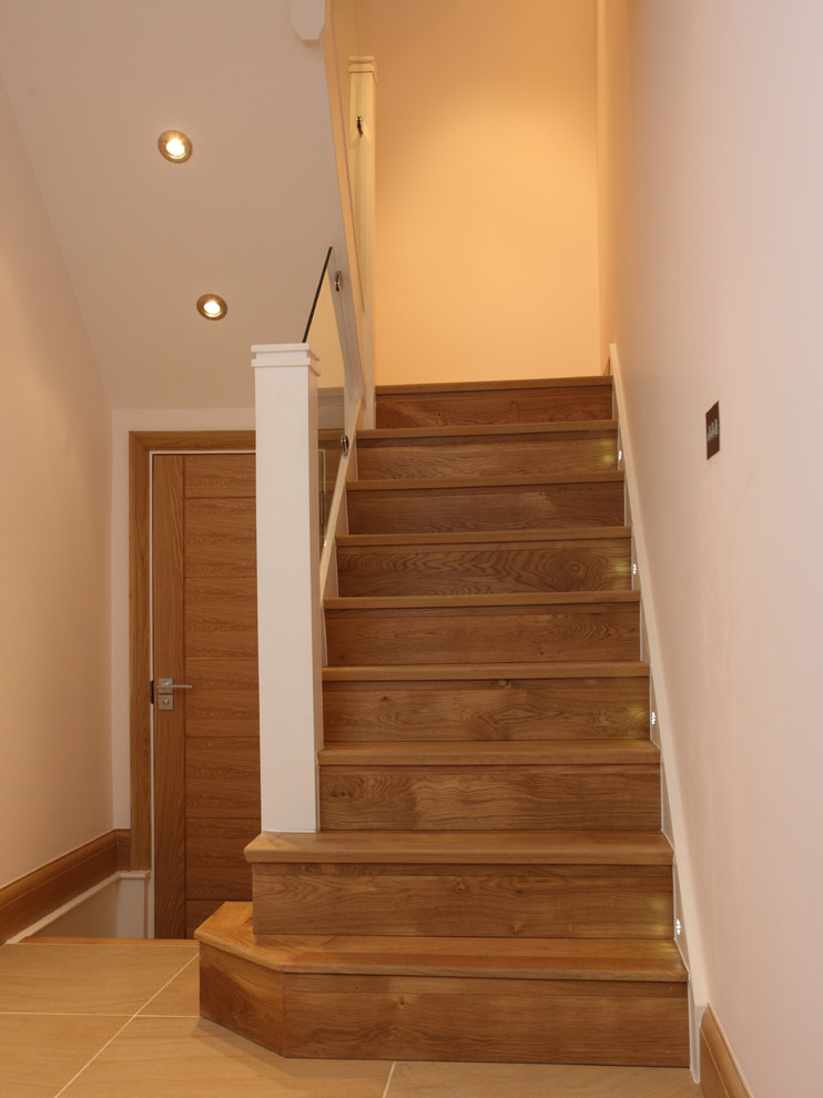 Ejemplo de escalera en U contemporánea de tamaño medio con escalones de madera, contrahuellas de madera y barandilla de vidrio