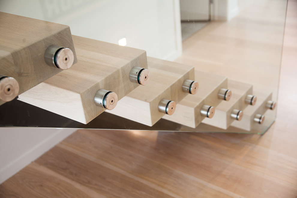 Esempio di una scala sospesa minimalista di medie dimensioni con pedata in legno e nessuna alzata