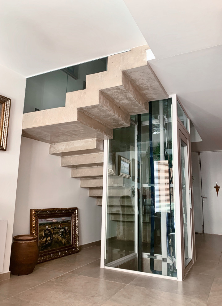 Modelo de escalera en L actual grande con escalones de hormigón, contrahuellas de hormigón, barandilla de vidrio y ladrillo