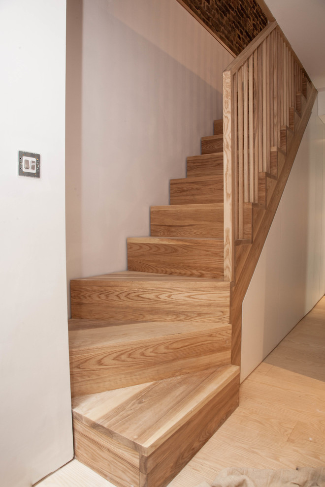На фото: п-образная деревянная лестница в современном стиле с деревянными ступенями и деревянными перилами с