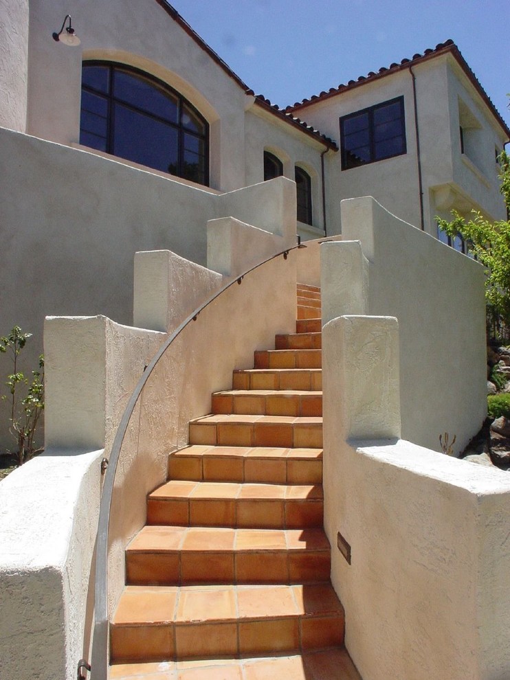 Свежая идея для дизайна: лестница в средиземноморском стиле с ступенями из терракотовой плитки, подступенками из терракотовой плитки и металлическими перилами - отличное фото интерьера
