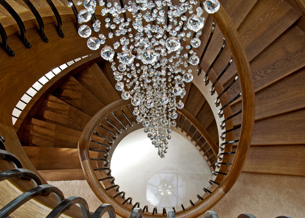 Свежая идея для дизайна: большая изогнутая деревянная лестница в стиле неоклассика (современная классика) с деревянными ступенями и металлическими перилами - отличное фото интерьера