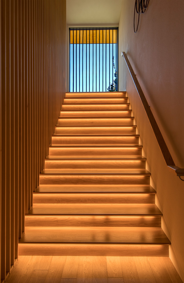 他の地域にあるラグジュアリーな広いコンテンポラリースタイルのおしゃれな直階段 (木材の手すり、木の蹴込み板) の写真