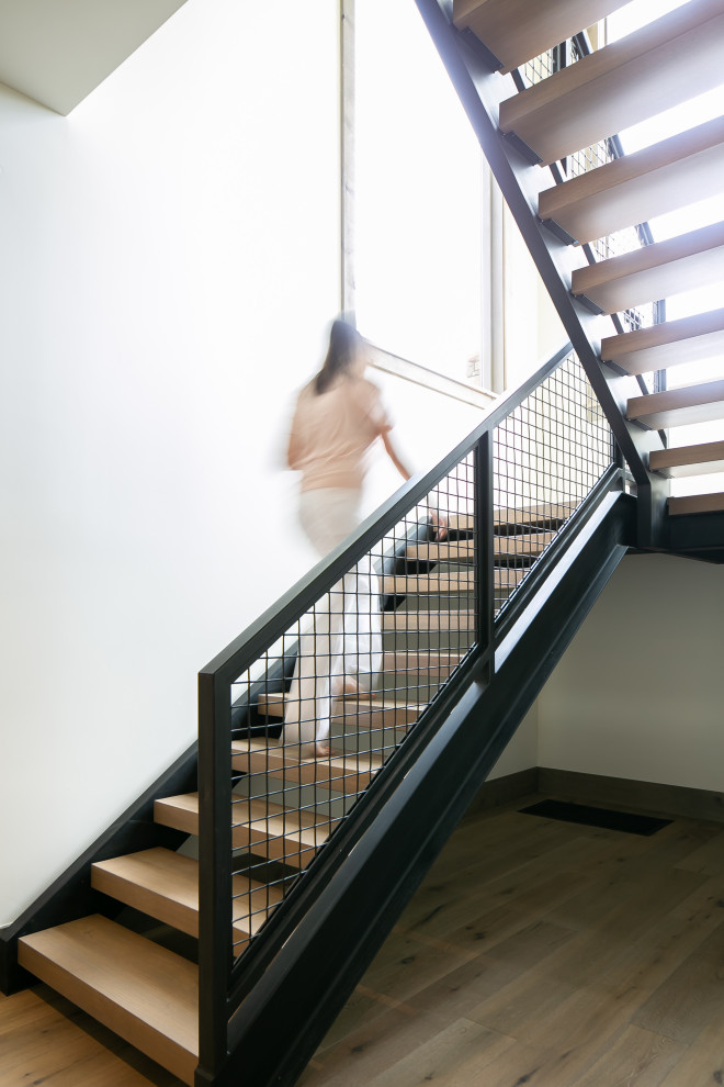 Réalisation d'un escalier chalet en L avec des marches en bois, des contremarches en métal et un garde-corps en métal.