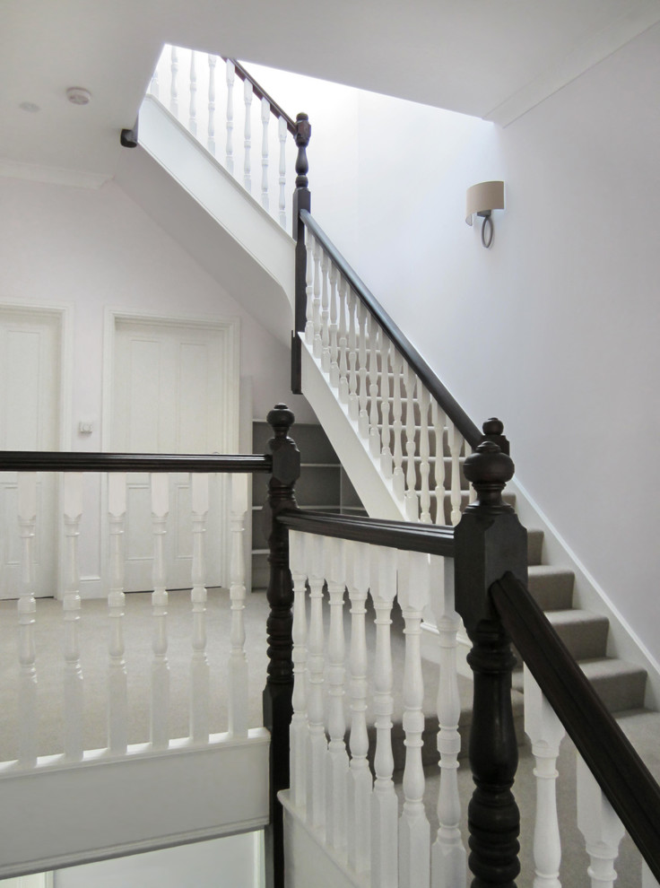 Medium sized traditional carpeted l-shaped wood railing staircase in London with carpeted risers.