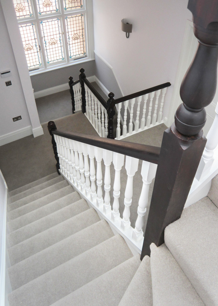 Photo of a medium sized classic carpeted l-shaped wood railing staircase in London with carpeted risers.