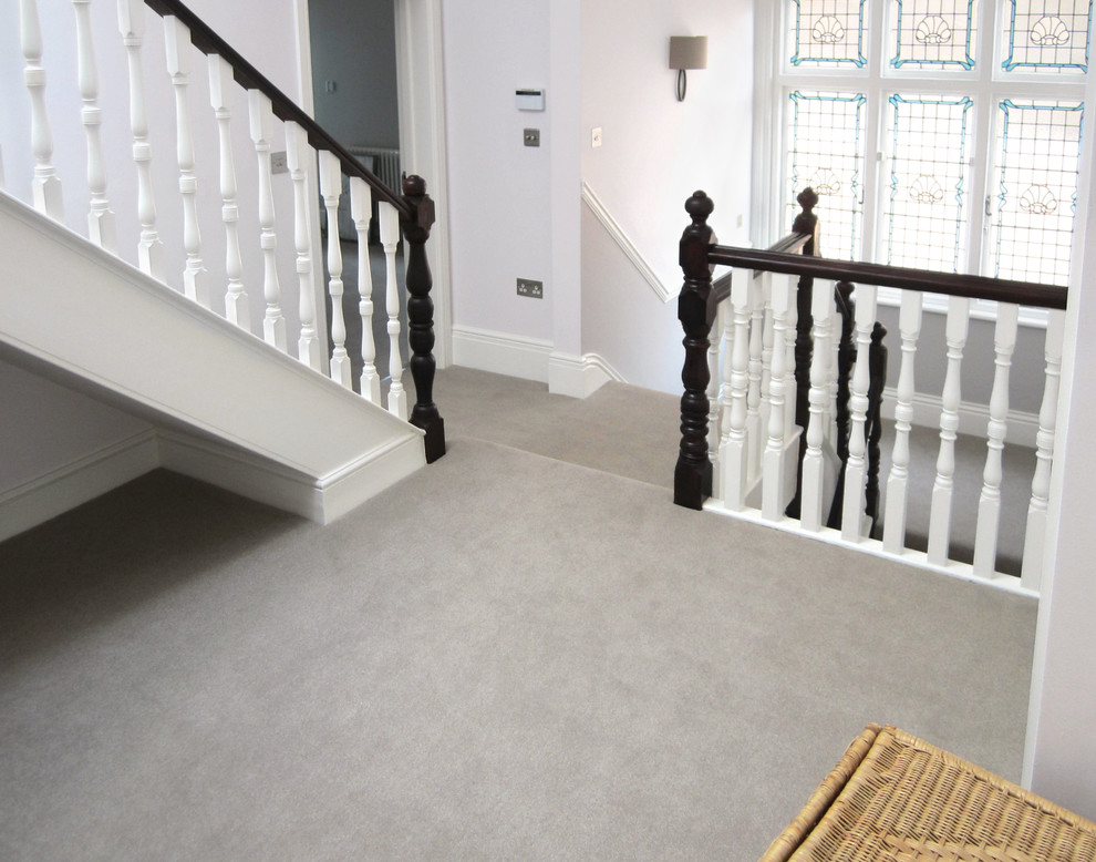 This is an example of a medium sized classic carpeted l-shaped wood railing staircase in London with carpeted risers.