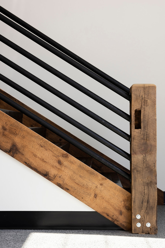 Imagen de escalera recta industrial de tamaño medio con contrahuellas de madera y barandilla de metal