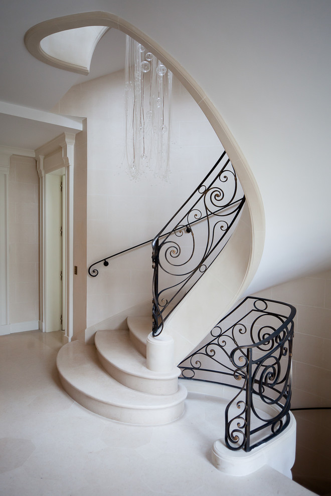 Photo of a large classic concrete curved staircase in Paris with feature lighting.