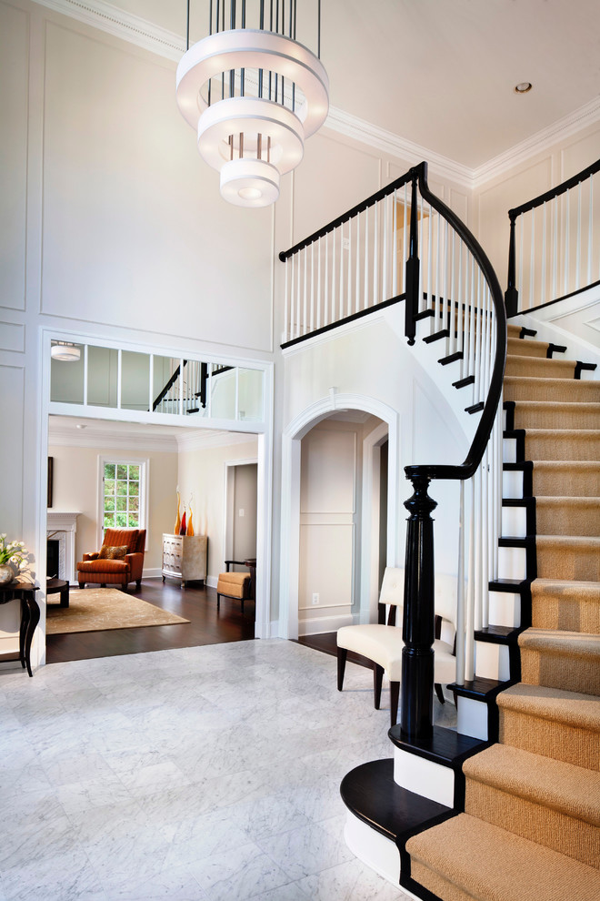 Стильный дизайн: огромная изогнутая лестница в классическом стиле с деревянными ступенями и крашенными деревянными подступенками - последний тренд