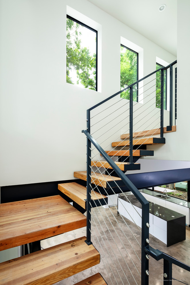 Ejemplo de escalera suspendida minimalista de tamaño medio con escalones de madera, contrahuellas de metal y barandilla de metal