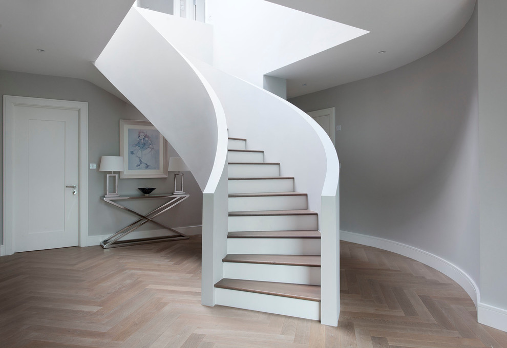 Idée de décoration pour un grand escalier courbe tradition avec des marches en bois et éclairage.