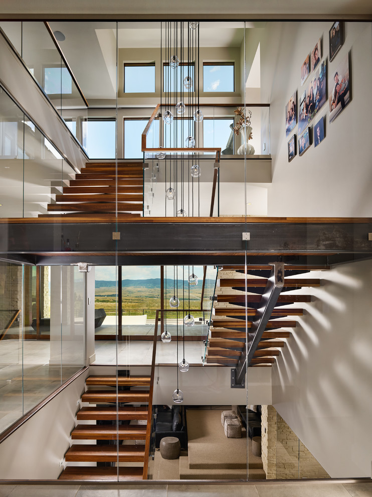 Exemple d'un très grand escalier sans contremarche flottant moderne avec des marches en bois et un garde-corps en verre.