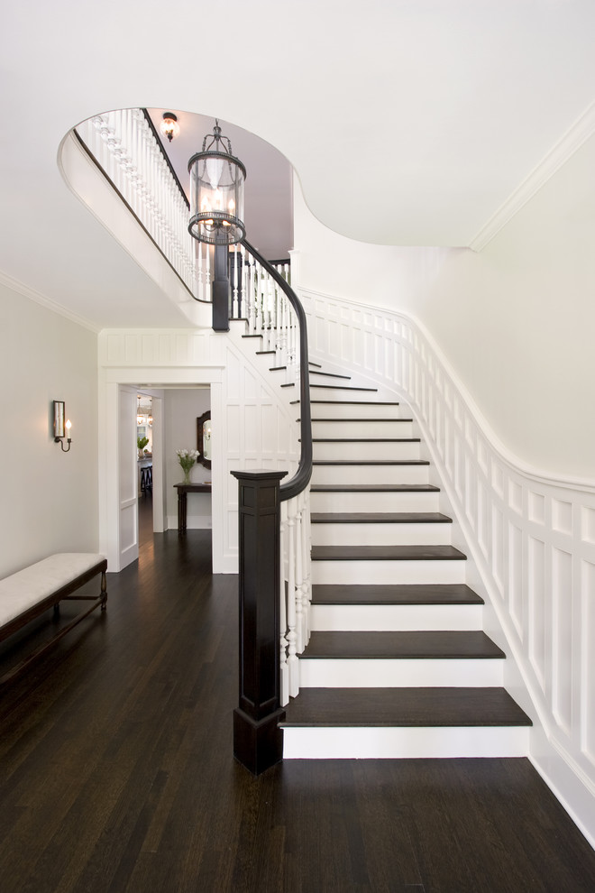 Example of a large classic wooden curved wood railing staircase design in New York with painted risers