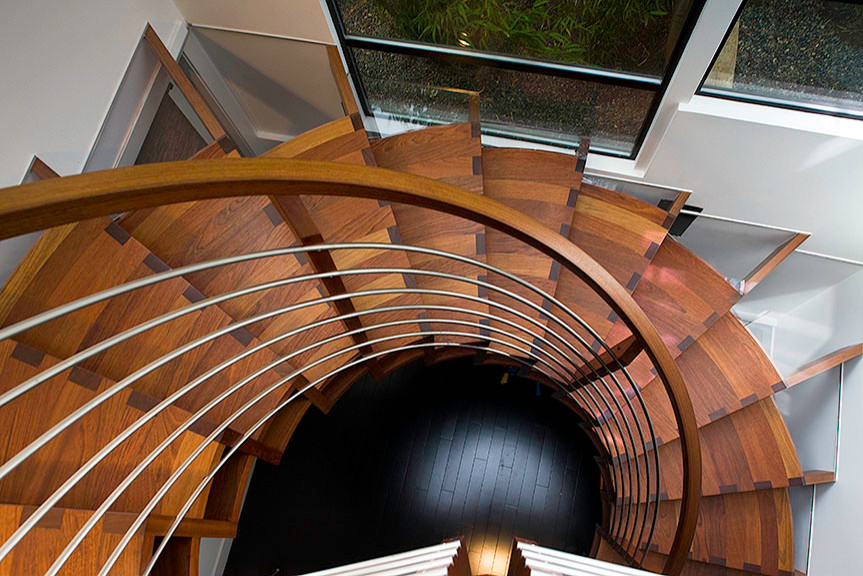 Ejemplo de escalera de caracol minimalista grande sin contrahuella con escalones de madera y barandilla de metal