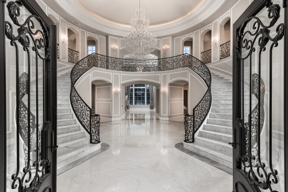 Foto på en mycket stor funkis svängd trappa i marmor, med sättsteg i marmor och räcke i metall