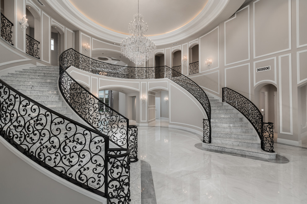 Свежая идея для дизайна: огромная изогнутая лестница в стиле модернизм с мраморными ступенями, подступенками из мрамора и металлическими перилами - отличное фото интерьера