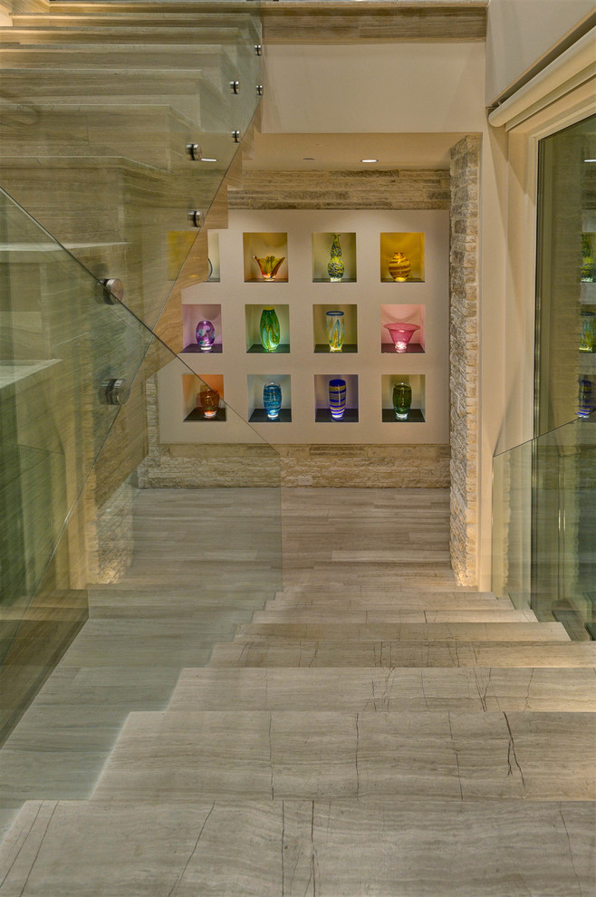 オーランドにあるラグジュアリーなコンテンポラリースタイルのおしゃれなスケルトン階段 (ライムストーンの蹴込み板、ガラスフェンス) の写真