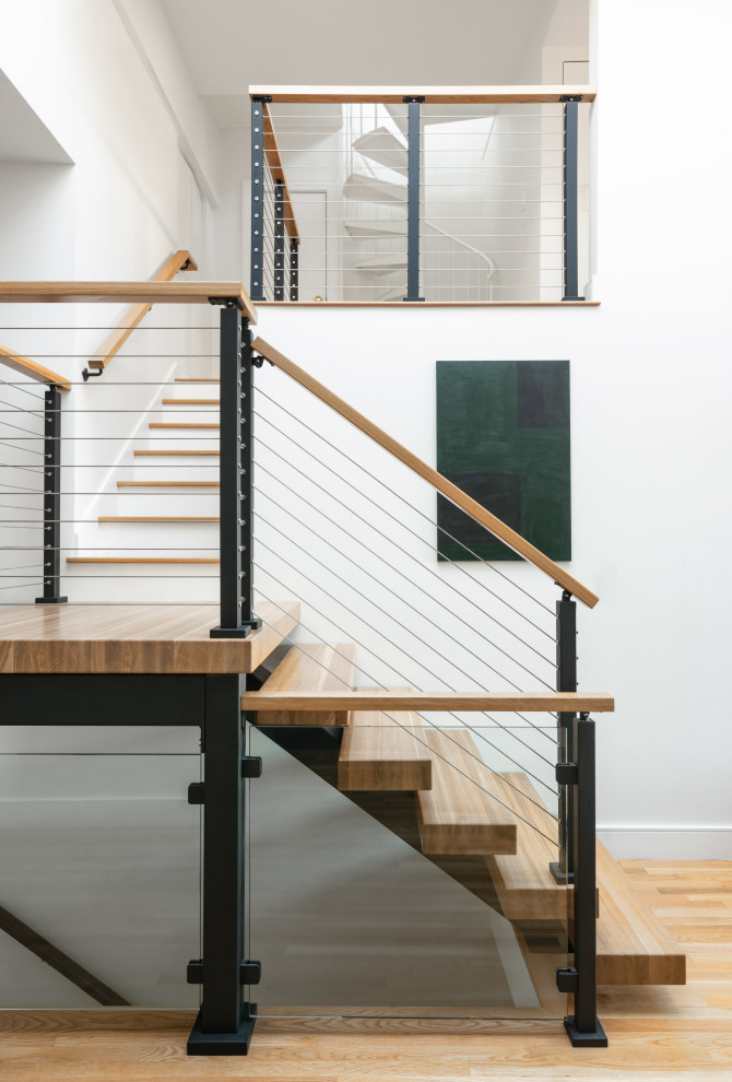 Imagen de escalera suspendida bohemia grande sin contrahuella con escalones de madera y barandilla de cable