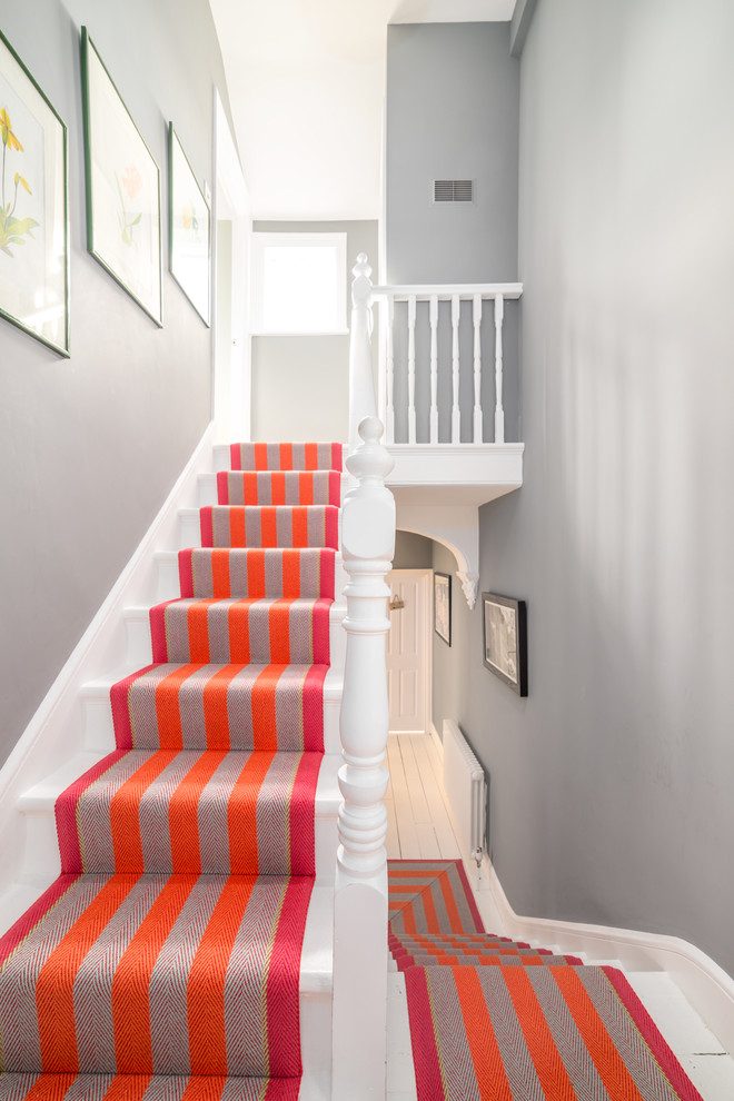 Пример оригинального дизайна: п-образная лестница в скандинавском стиле с крашенными деревянными ступенями, крашенными деревянными подступенками и деревянными перилами