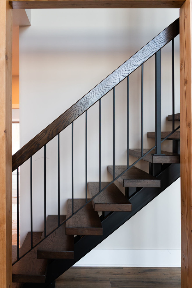 На фото: металлическая лестница на больцах в современном стиле с деревянными ступенями и перилами из смешанных материалов