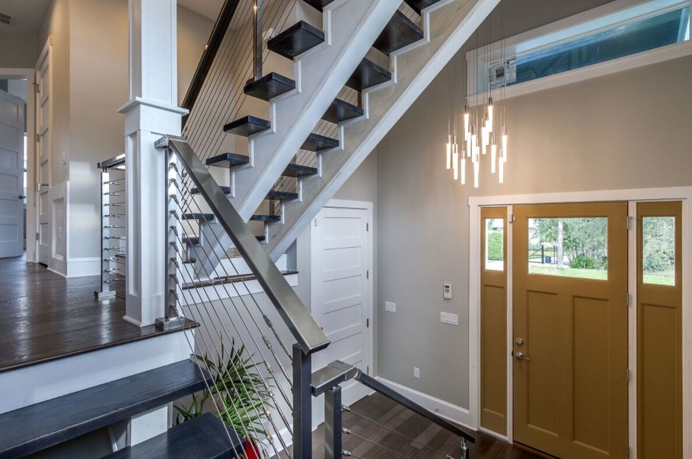 Photo of a large contemporary wood u-shaped wire cable railing staircase in Tampa with open risers.