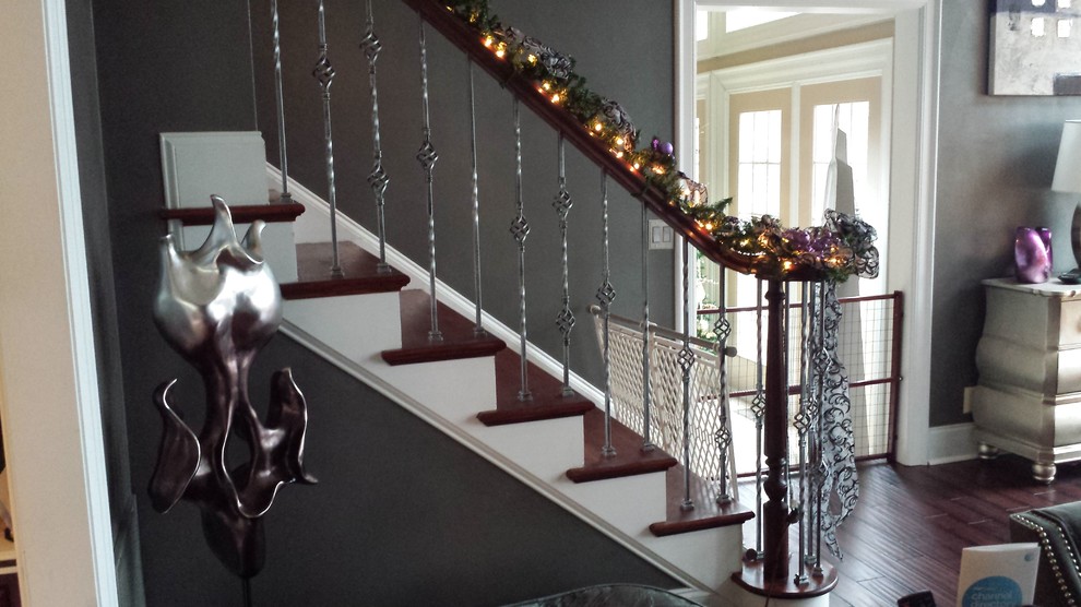 Large tuscan wooden curved staircase photo in Charlotte with painted risers