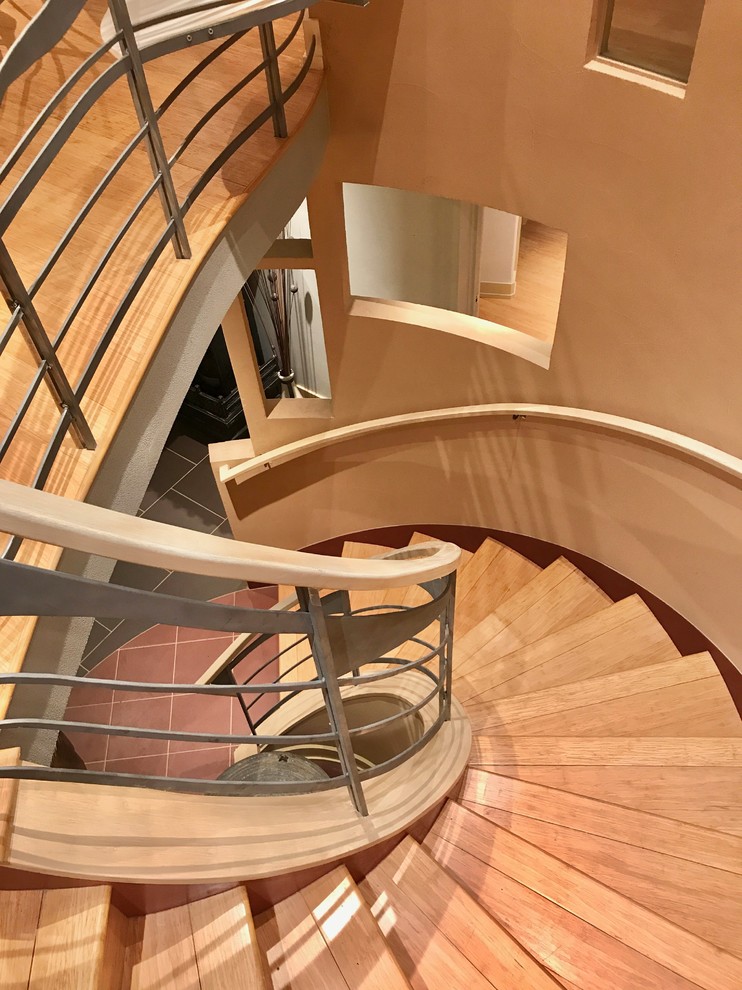 Пример оригинального дизайна: изогнутая деревянная лестница среднего размера в стиле фьюжн с деревянными ступенями и перилами из смешанных материалов