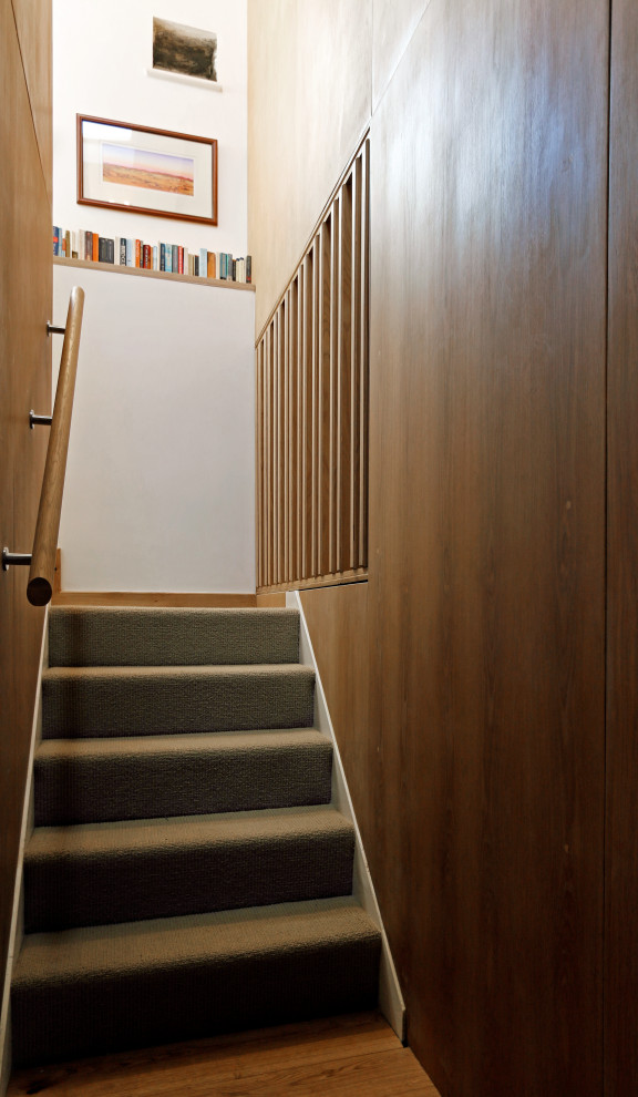 Ejemplo de escalera en U contemporánea de tamaño medio con escalones enmoquetados, barandilla de madera y madera