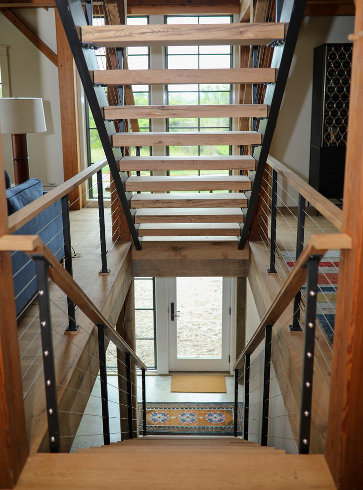 Пример оригинального дизайна: большая прямая лестница в стиле кантри с деревянными ступенями и металлическими перилами без подступенок