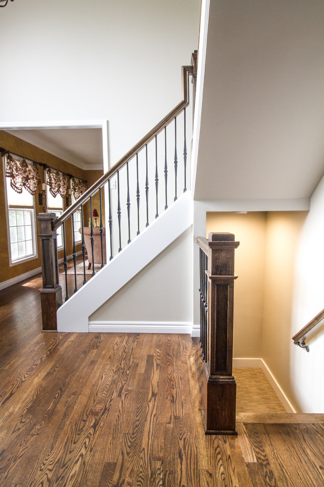 На фото: угловая деревянная лестница среднего размера в стиле неоклассика (современная классика) с ступенями с ковровым покрытием с