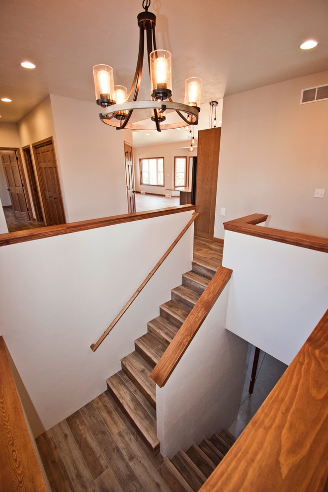 Diseño de escalera en U de estilo de casa de campo de tamaño medio con escalones de madera, contrahuellas de madera y barandilla de madera