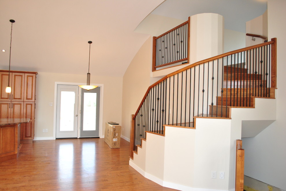 Mid-sized elegant wooden curved metal railing staircase photo in Other with wooden risers