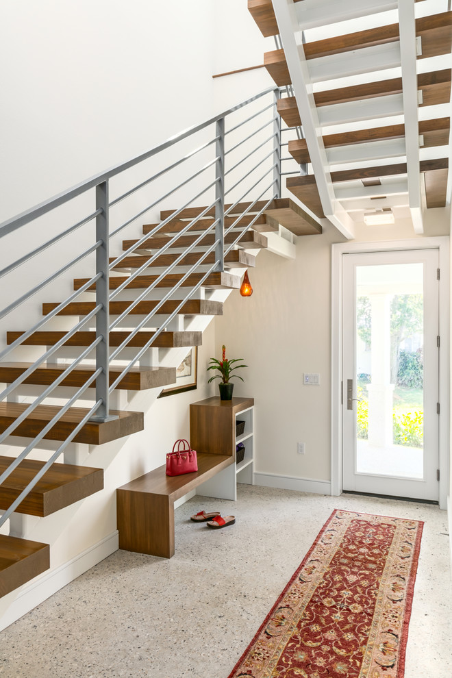 На фото: большая п-образная лестница в стиле неоклассика (современная классика) с деревянными ступенями и металлическими перилами без подступенок